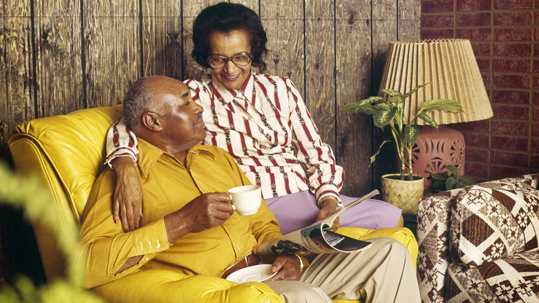 1970s mature couple sits on a leather yellow chair