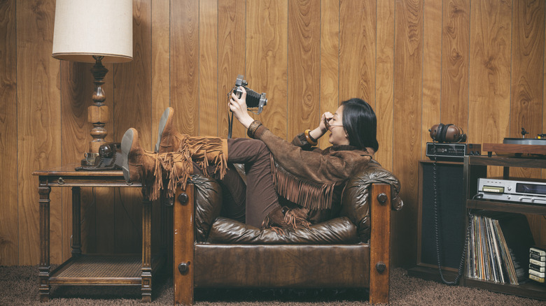 Woman sitting in a chair in front of wood-paneled wall