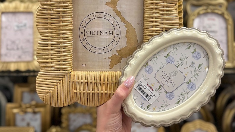 Person holds up two picture frames to the camera, one in woven rattan, the other in white ceramics