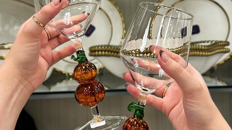 Person holds two glasses with stems shaped like pumpkins
