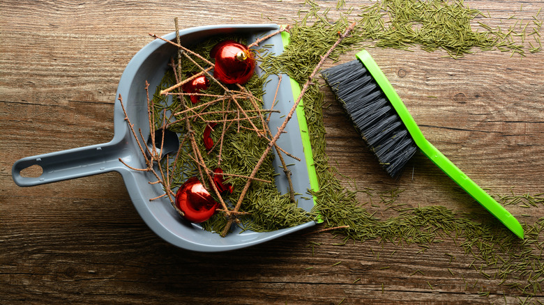 Handheld broom and dustpan with Christmas tree needles, sticks and decorative balls