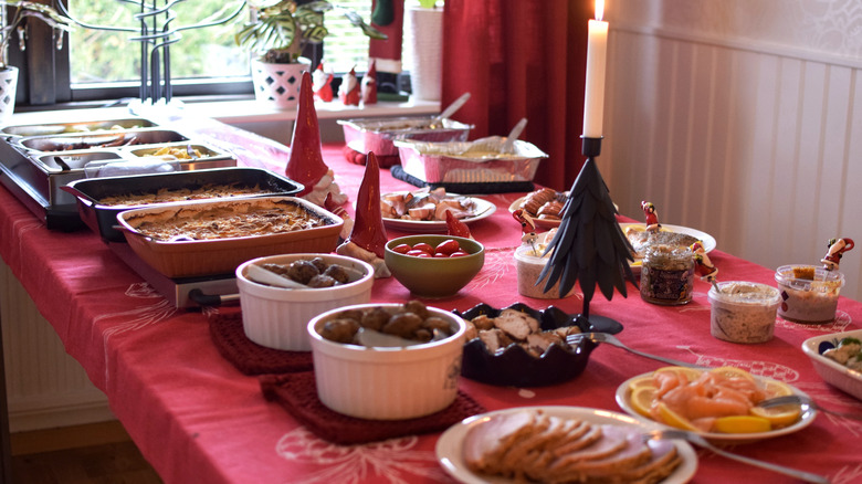 Food lined up on a table with a red table cloth and Christmas decorations on the table
