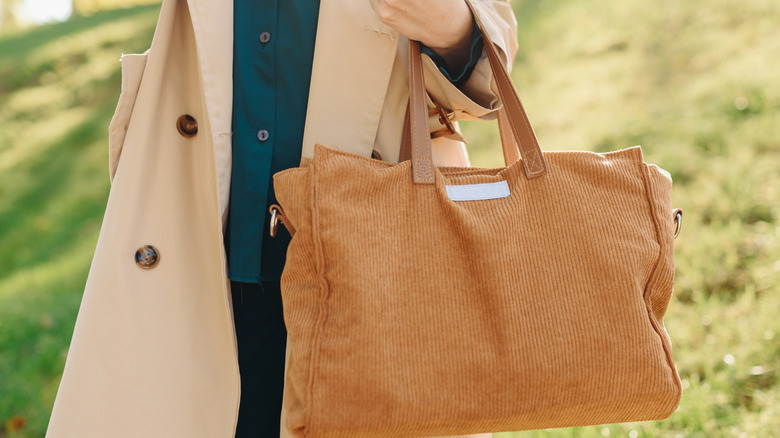 Woman wearing a coat and carrying a large brown purse
