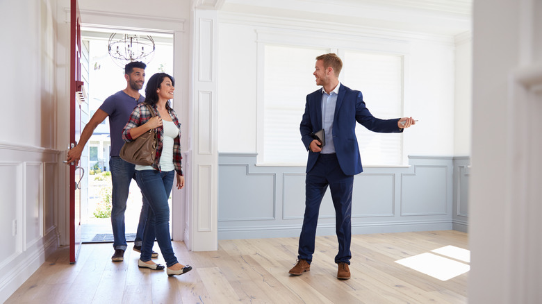 Real estate agent showing a couple into to view a listed home