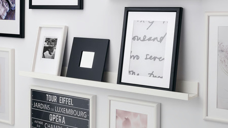 An assortment of framed pictures sit on a MOSSLANDA  picture ledge from IKEA