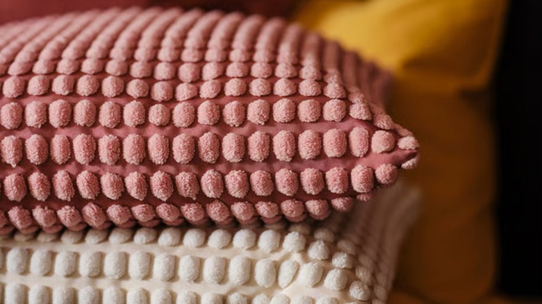 Cushions covered in pink and off-white SVARTPOPPEL covers from IKEA are stacked on top of each other