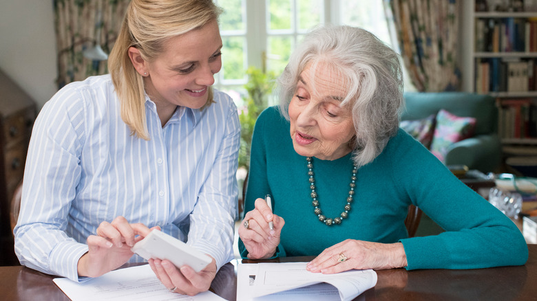 younger woman helping elderly woman with finances