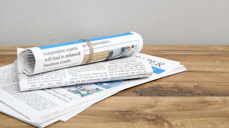 A rolled newspaper on a table