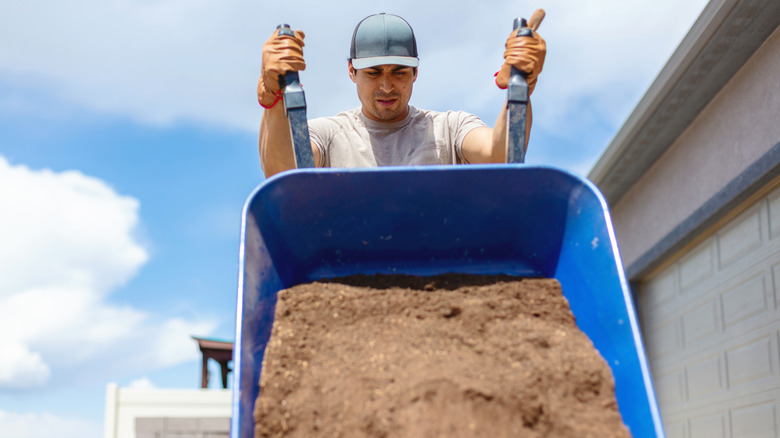 A person dumping a wheelbarrow full of dirt