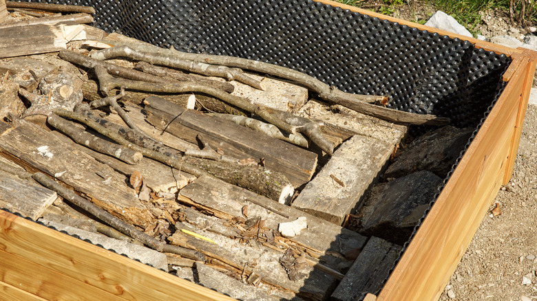 A raised garden bed filled with logs