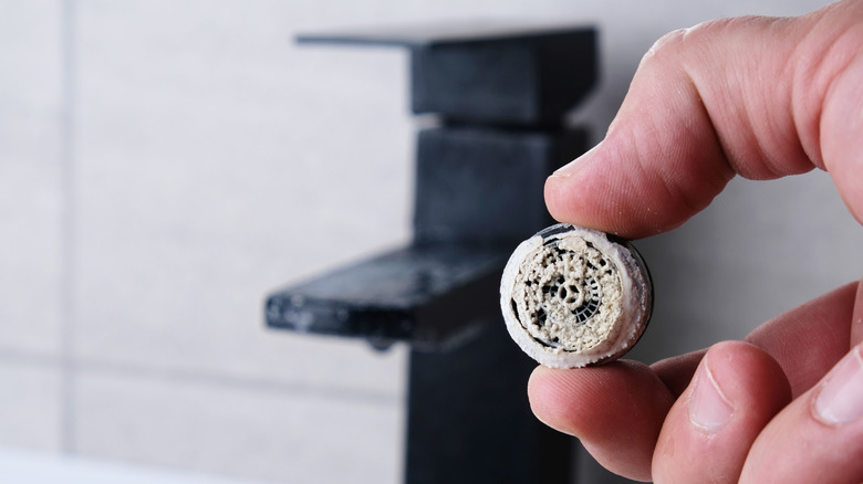 Man holding a limescale-encrusted sink aerator