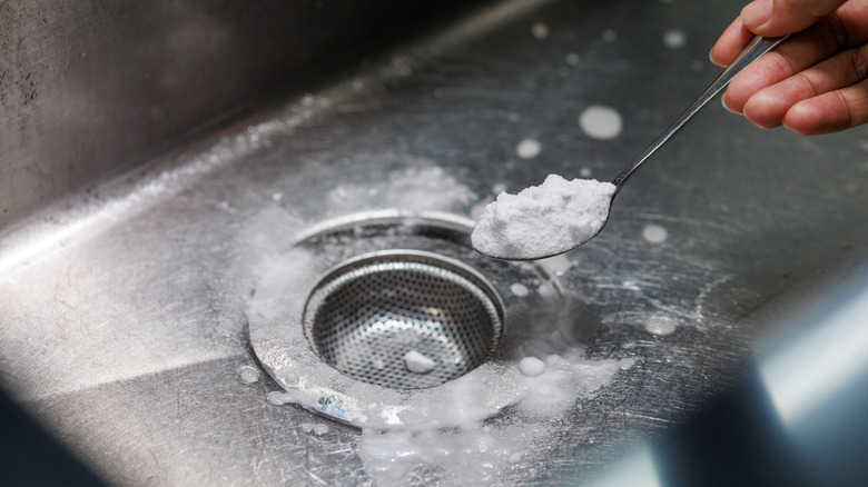 Woman using soda crystals in a sink drain