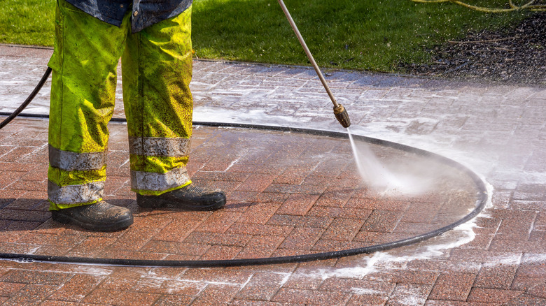 Worker cleaning a driveway with a pressure wash