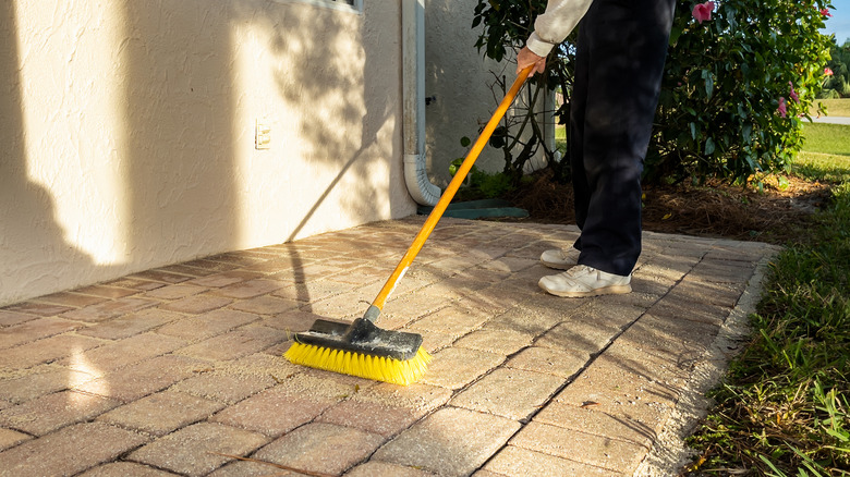 Person sweeping paving outside their home