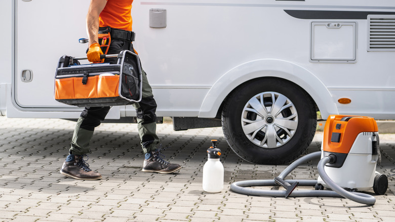 Man carrying a bag with a vacuum cleaner and cleaning bottle outside