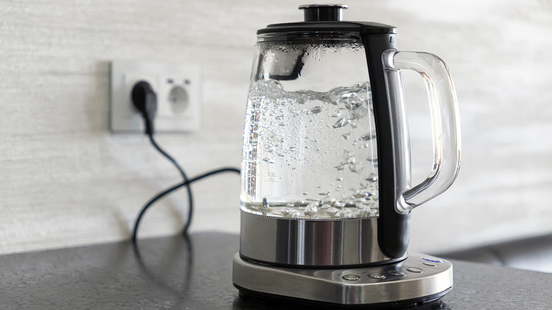 A glass kettle with boiling water on a counter