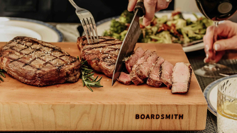 A Boardsmith cutting board used to slice and serve a steak