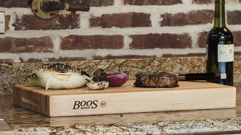 A steak and grilled onions on a Boos Block cutting board