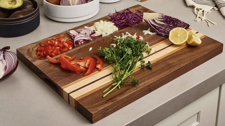 A cutting board holding peppers, onions, cabbage, lemon, and cilantro