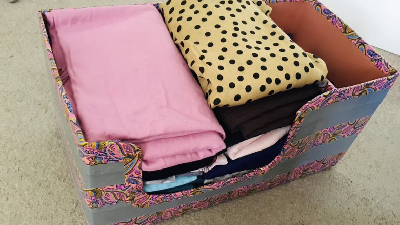 A used Costco cardboard box redecorated and used as clothing storage.