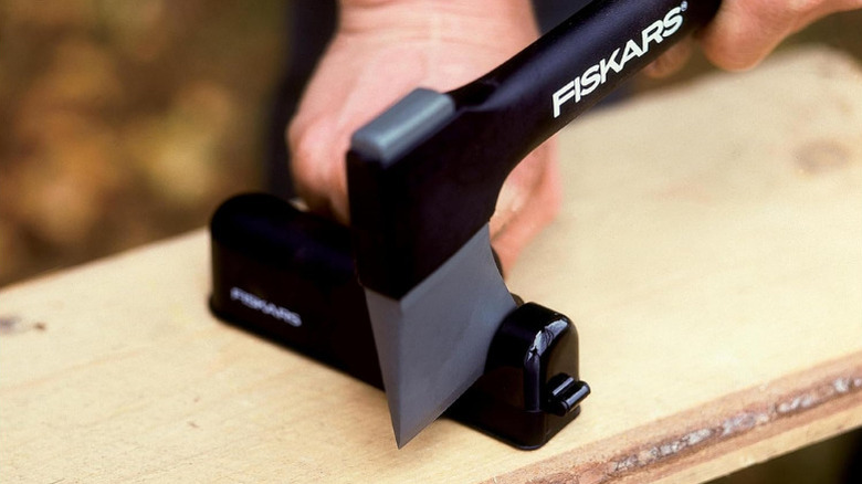 Close-up of a person sharpening an axe on Fiskars' Matte Plastic Axe and Knife Sharpener
