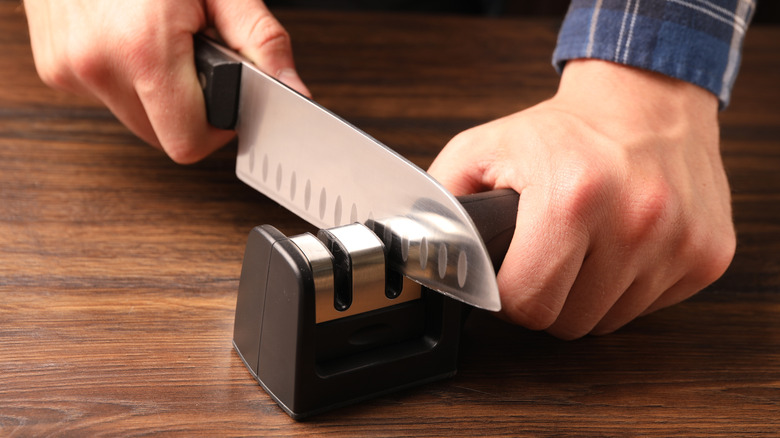 A man sharpening a knife on a countertop sharpening gadget