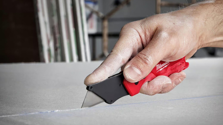 Close-up of a person using Milwaukee's Fastback Press and Flip Folding Utility Knife