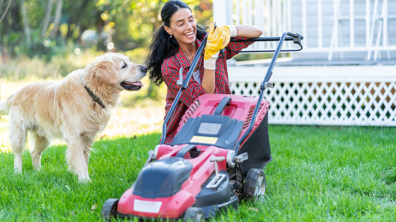 woman and dog with electric lawn mower