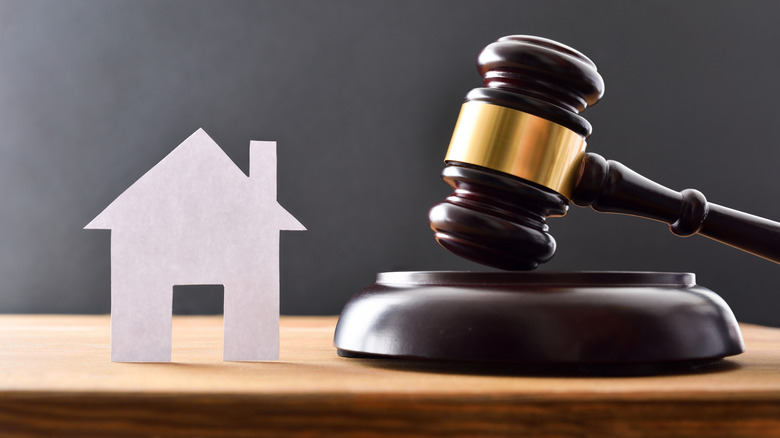 Judge's gavel next to a paper cutout of a home on a table
