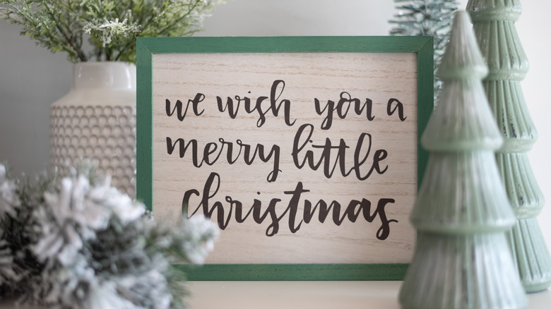 A wooden sign that says "we wish you a merry little Christmas."