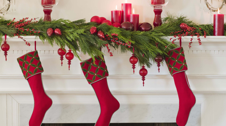 Matching red stockings hanging on a white fireplace.