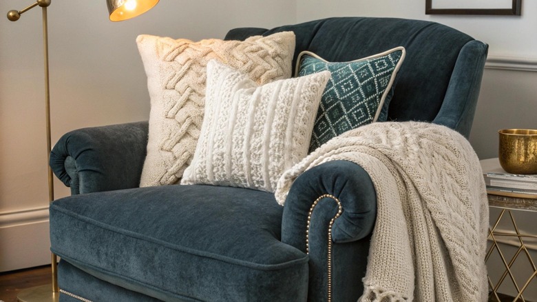 Velvet teal chair with cozy pillows and blanket