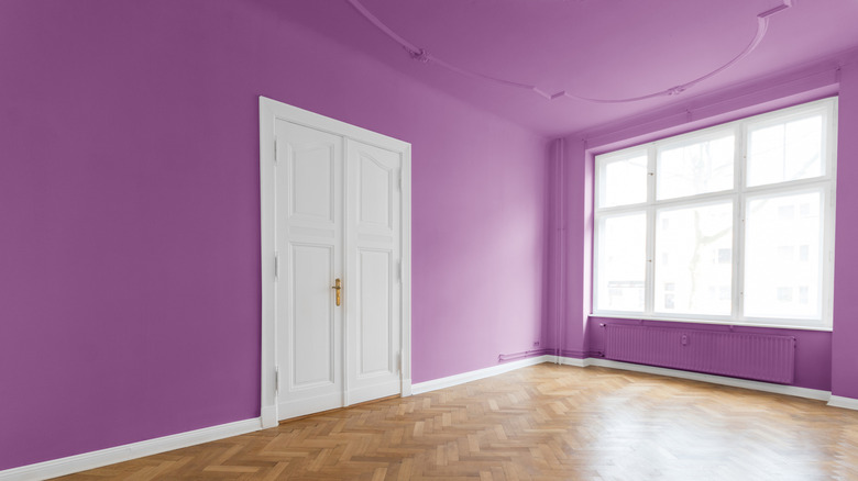 empty room with wooden floors, white door, and purple ceiling and walls