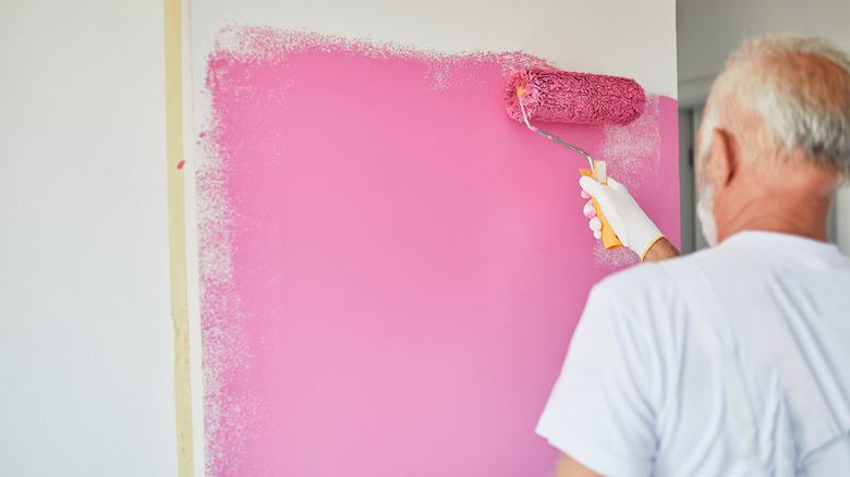 A man paints a wall pink