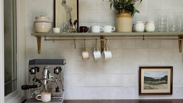 A brass gallery rail under shelf with mugs