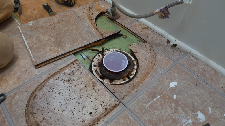 a damaged floor around a leaky toilet being repaired
