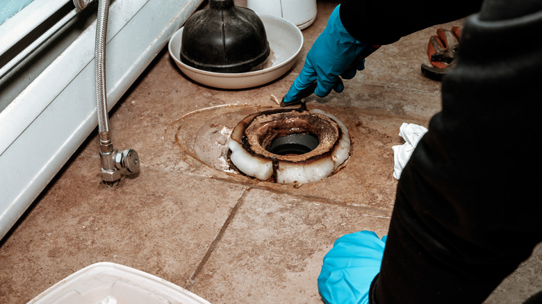 a plumber points at a cracked wax ring after a toilet has been removed