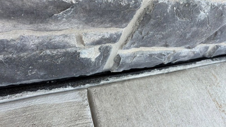 close-up of gap between cement patio and stone wall