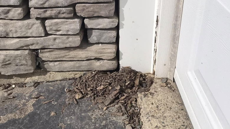 Soil and mulch accumulating at base of retaining wall, where it meets garage door of a house