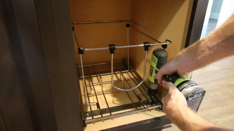 man installing pull-out trash slider