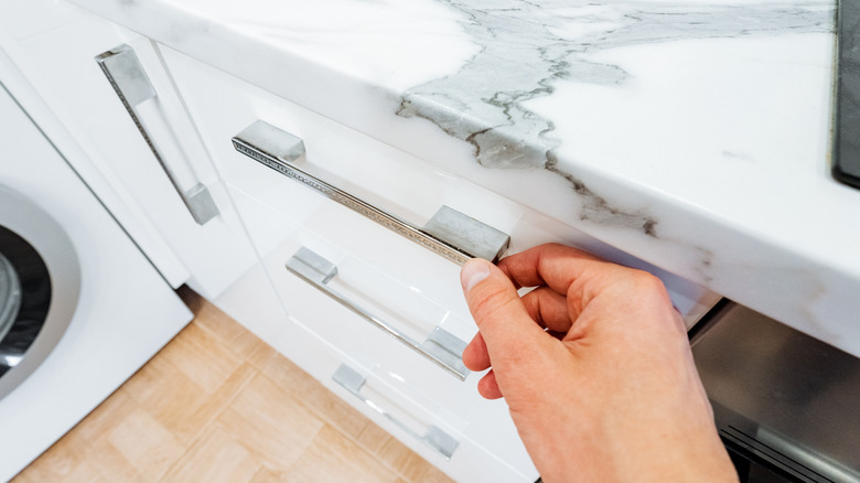 Person holding a silver drawer pull