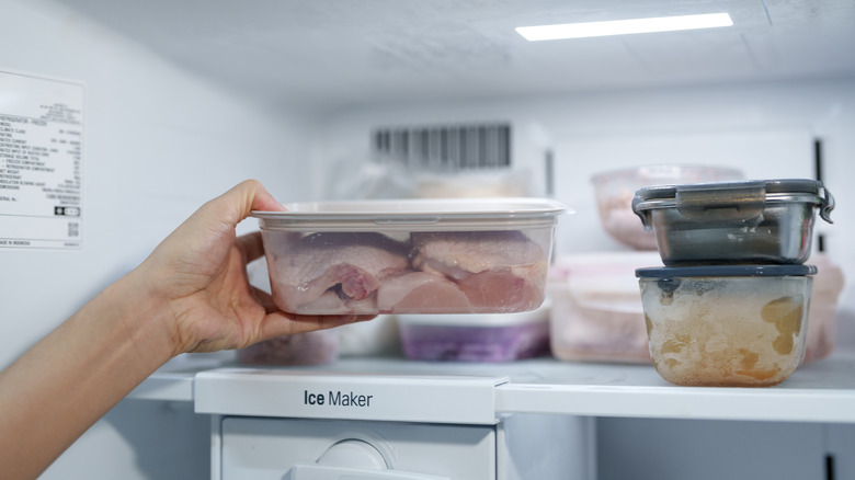 Person organizing freezer with several containers of food on a shelf