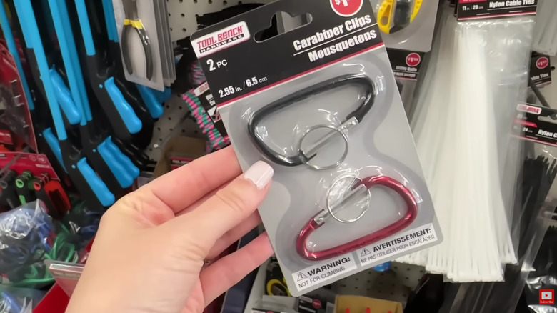 Close up of a hand holding a package of carabiners