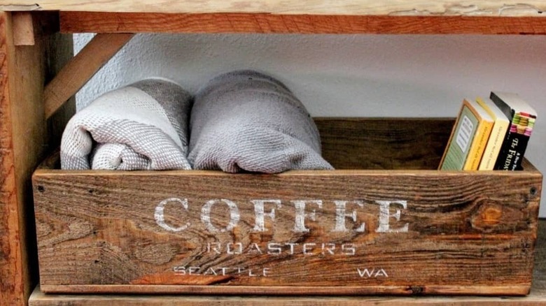 Rolled up throws in a wooden crate next to books