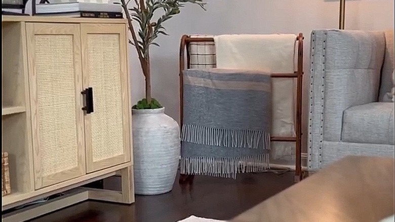 A quilt rack being used in a living room to hang blankets