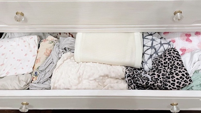 A dresser drawer being used to store blankets and sheets
