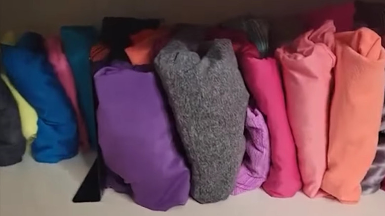 A bookend being used to keep folded clothes upright and organized