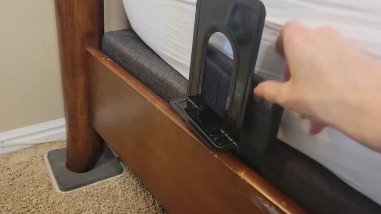 A bookend tucked into the side of a bed holding a phone