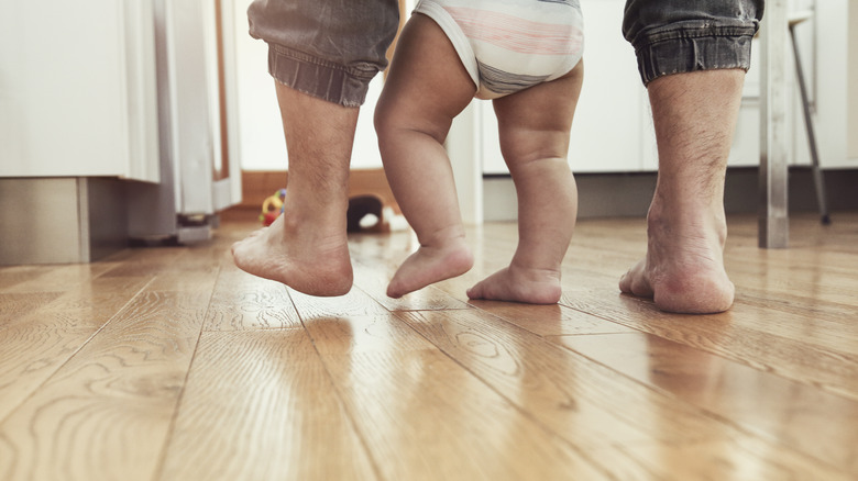 baby and parent walking on wood floors