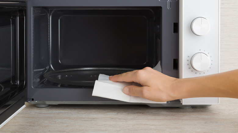 Hand wiping the inside of microwave